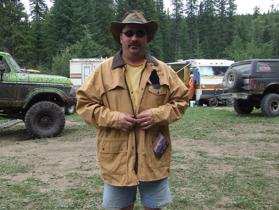Man in tan jacket and cowboy hat with off-road vehicles and RVs in background