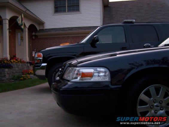 Black sedan parked in front of a house, with a black SUV behind it