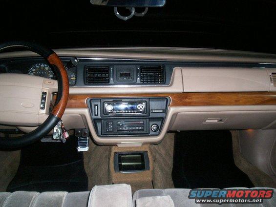 1992 Ford Crown Victoria interior dashboard with wood trim, aftermarket stereo, and tan upholstery