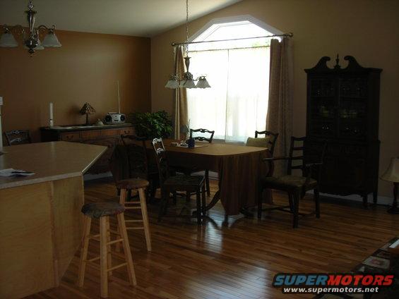 Interior of a dining room with a table, chairs, a hutch, and a kitchen island