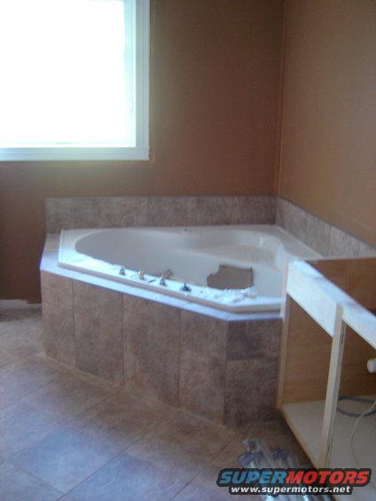 Bathroom with a tiled corner jacuzzi tub and a window