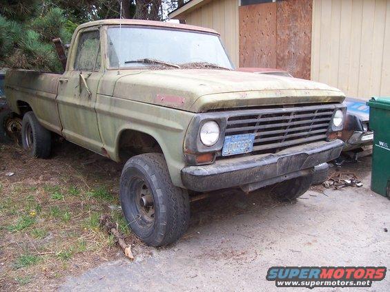 Green pickup truck with blue license plate, front 3/4 view