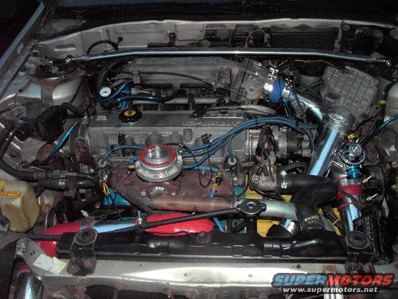 Engine bay with aftermarket turbocharger and intercooler piping. Silver paint on the engine block and valve cover