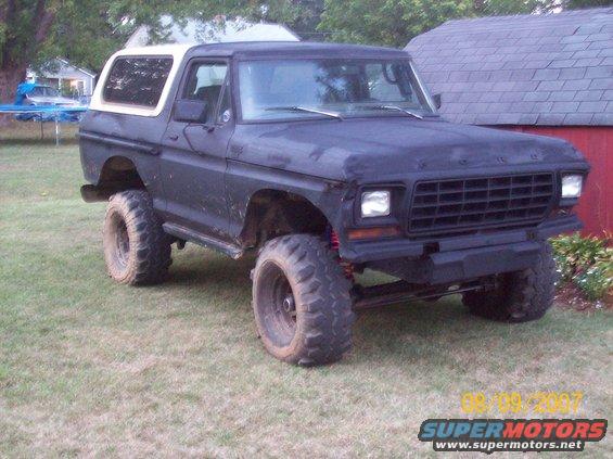 Lifted 1978 Ford Bronco with aftermarket bumper and large tires parked on grass