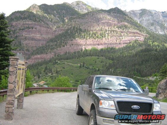 Ford F-150 parked on a mountain road with layered rock formations behind it