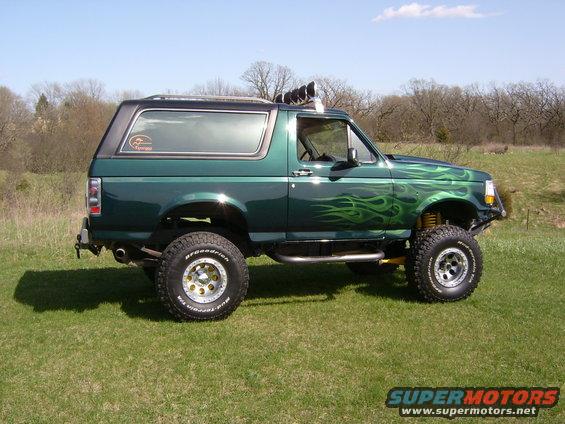 Lifted green SUV with flame decals on the side, parked on grass