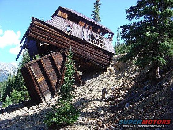 Dilapidated wooden building on a rocky slope under a blue sky