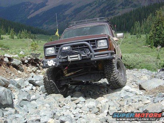 1986 Ford Bronco II navigating a rocky mountain trail with a winch and roof rack
