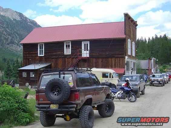 Brown Ford Bronco II with a spare tire on the back, lifted suspension, and roof rack