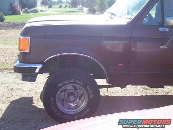 Maroon Ford F-Series truck, front quarter view, lifted suspension, off-road tires