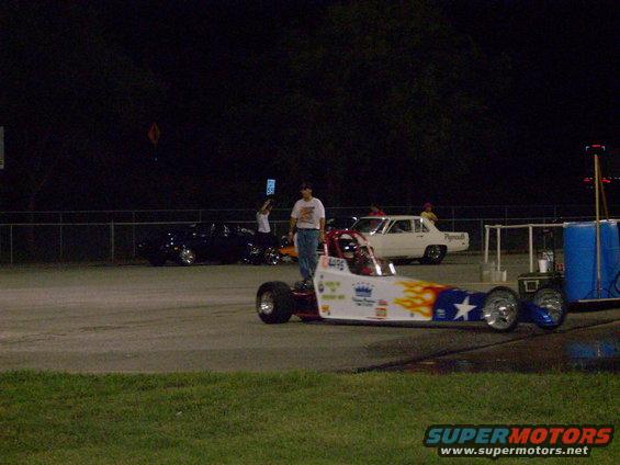 Dragster with flames and stars on side, parked on track
