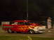 1991 Ford Mustang - A custom drag car with flame decals sits on the track at night, with a spectator watching.