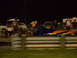1991 Ford Mustang - A dragster with vibrant flame graphics is visible on a track at night, with several people and other vehicles in the background.