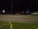 1991 Ford Mustang - A drag racing car and a sedan are parked on a track at night, with a person standing in the foreground.