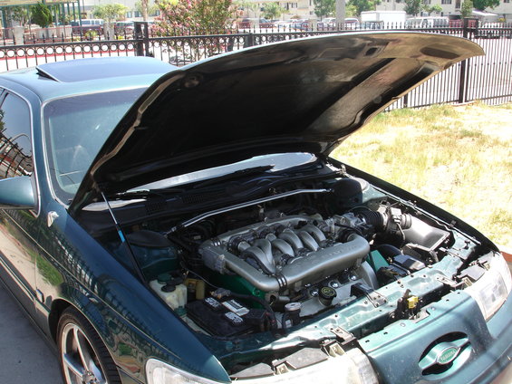 Dark green sedan with hood open showing V6 engine and intake. Sunroof visible