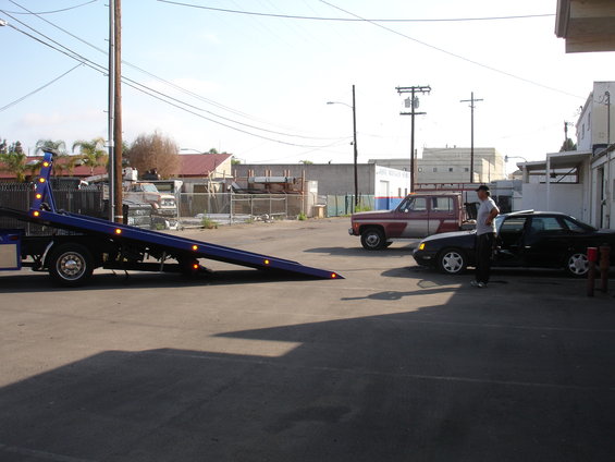 1991 Ford Taurus sedan parked next to a tow truck and a pickup truck
