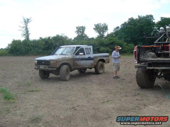 Muddy pickup truck with snorkel and off-road tires, parked in a field