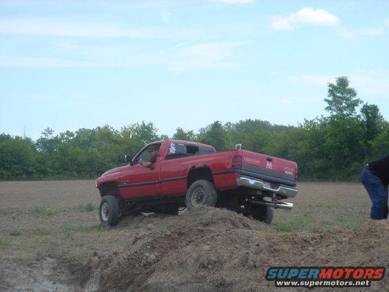 Red pickup truck with lifted suspension driving on a dirt mound