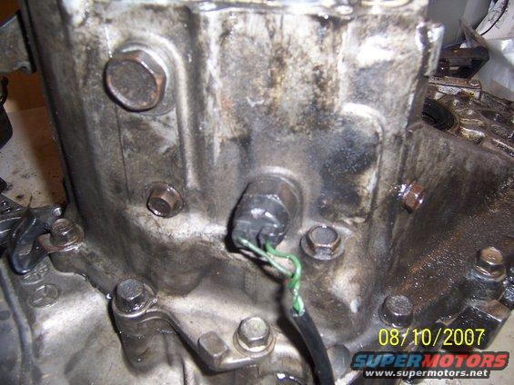 Close-up of a transmission housing with a sensor and green wires attached. Date stamp reads 08/10/2007