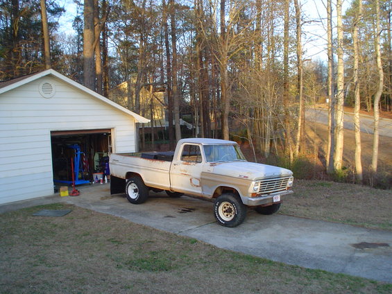 White 1967 Ford F-250 pickup truck parked in driveway next to a garage