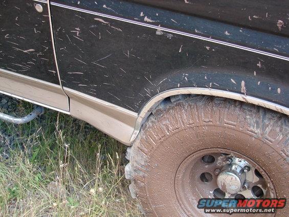 Mud-splattered dark green 1992 Ford Bronco side view, showing the front fender, door, and wheel