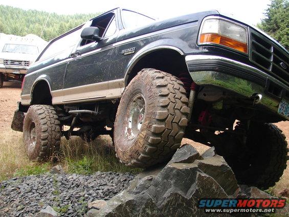 Lifted dark blue 1996 Ford Bronco climbing rocks