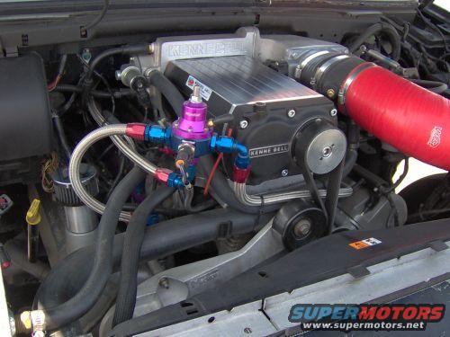Engine bay with a Kenne Bell supercharger, purple fuel pressure regulator, and red intake tube