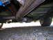 2003 Ford Mustang - The underside of a vehicle, showing the exhaust pipe and a rear wheel, is captured from a low angle.