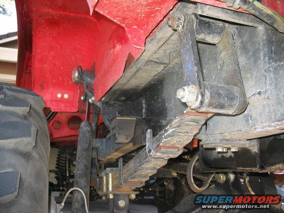 Red vehicle body, large tire, leaf spring suspension, and black chassis parts. Watermark reads SUPERMOTORS