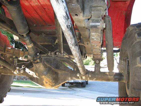 Undercarriage view of red off-road vehicle's rear axle and suspension components