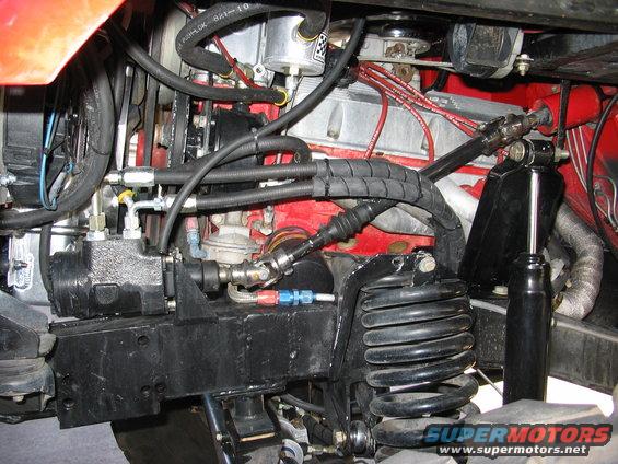 Engine bay with red engine block, black steering components, and large coil spring
