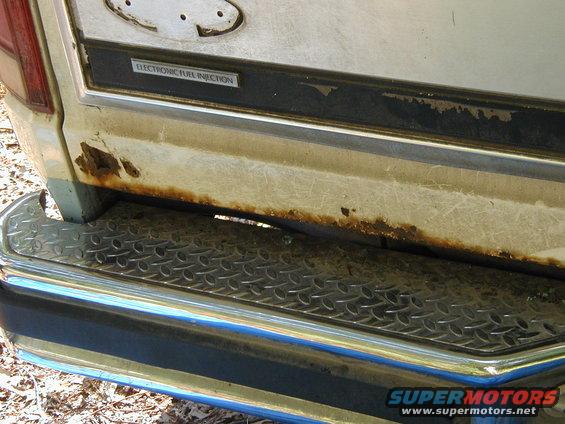 1986 Ford Bronco rear tailgate with 'ELECTRONIC FUEL INJECTION' badge and rusty lower panel above chrome bumper