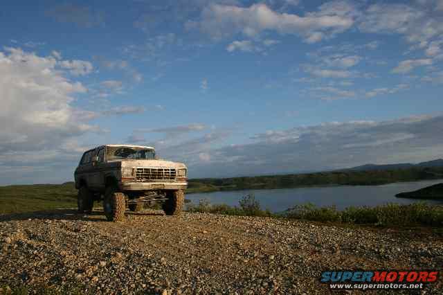 Old Ford Bronco parked on a rocky hill overlooking a lake