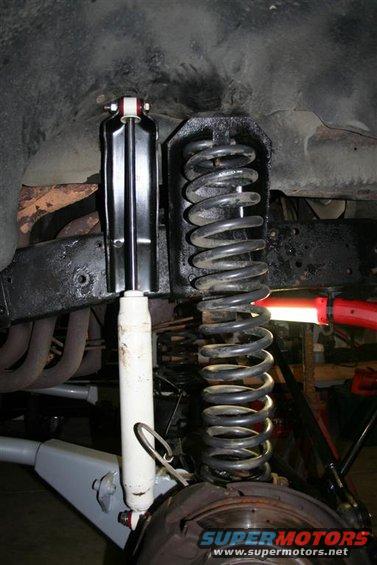 Close-up of a vehicle's front suspension with a shock absorber and coil spring