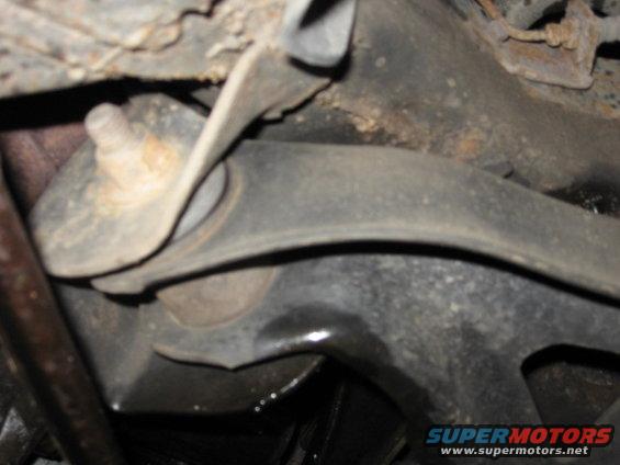 Close-up of a rusty vehicle suspension part with a bolt and rubber bushing