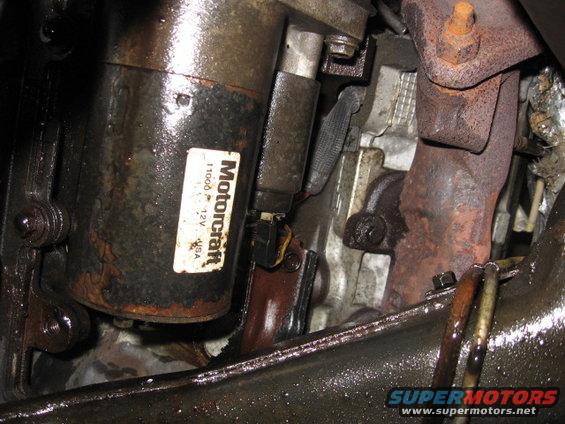 Motorcraft starter motor with 12V USA label, next to rusty exhaust manifold