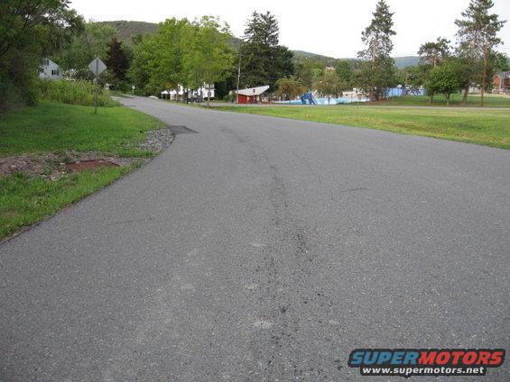 Empty road leading towards houses and a park with a swimming pool