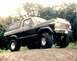 1979 Ford Bronco - This lifted 1979 Ford Bronco is shown in a three-quarter front view, parked on a dirt path with trees in the background.