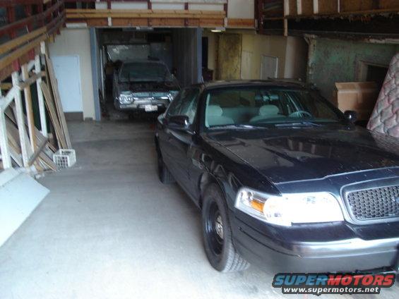 Black 2000 Ford Crown Victoria parked in garage with another car behind it