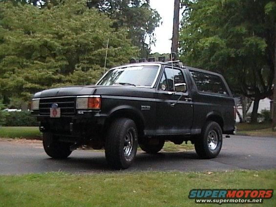 Black 1990 Ford Bronco parked on asphalt with trees in background