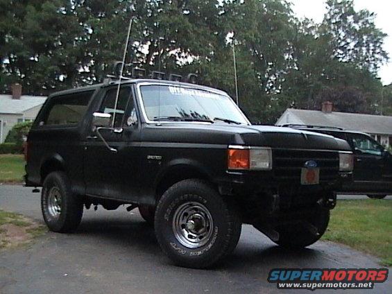 Black Ford Bronco with roof lights and antennas parked in a driveway