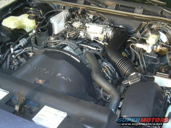 Engine bay with a black fan shroud that says "CAUTION FAN"