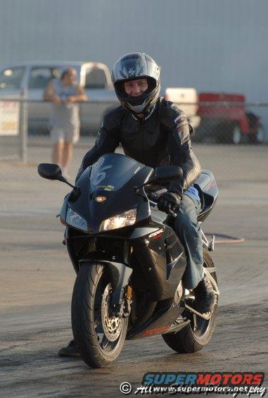 2006 Honda CBR-RR sportbike with rider wearing helmet and leather jacket at drag strip