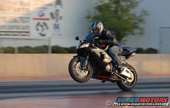 Black 2006 Honda CBR-RR motorcycle doing a wheelie on a drag strip