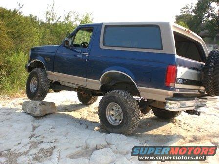 Blue and tan 1996 Ford Bronco with lifted suspension on rocks