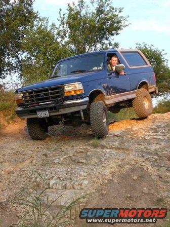 Blue 1996 Ford Bronco driving off-road on rocky terrain