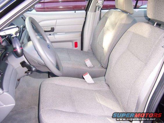 Car interior showing front seats, steering wheel, and dashboard. A red light is visible on the door panel