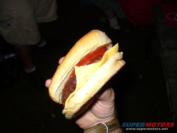 hand holding a hot dog with cheese and ketchup