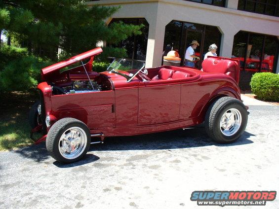 Red convertible hot rod, hood open, showing engine. Side view