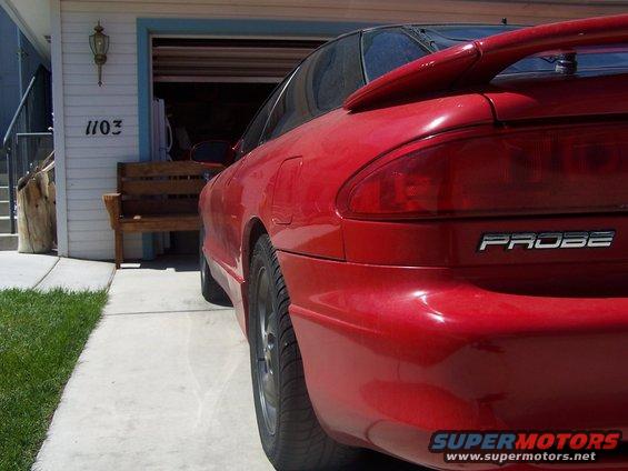Red coupe parked in front of a garage. The word PROBE is visible on the rear